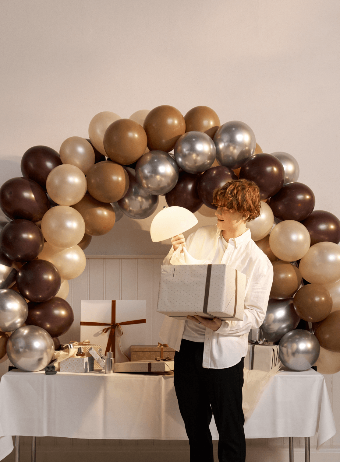 Panthella 250 Portable bordlampe holdt ved indendørs fejring med balloner og gaver, © 2025 Louis Poulsen.