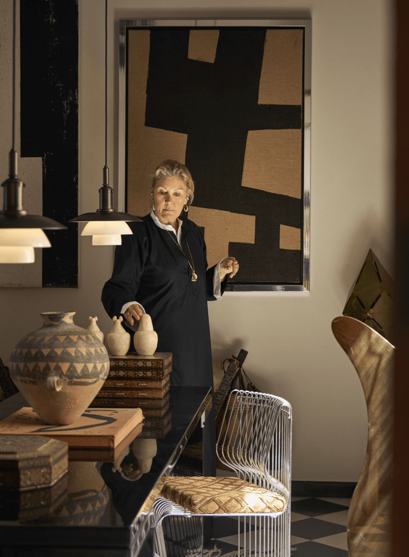 Two pendant lamps softly illuminating an eclectic dining room with art and pottery, © 2025 Louis Poulsen.