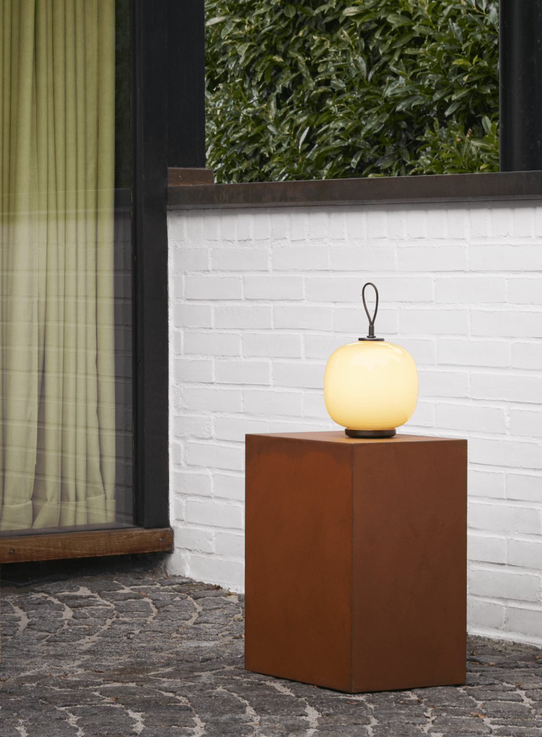 Lámpara de mesa VL45 Portable en vidrio opalino colocada sobre un pedestal en exterior, © 2025 Louis Poulsen.