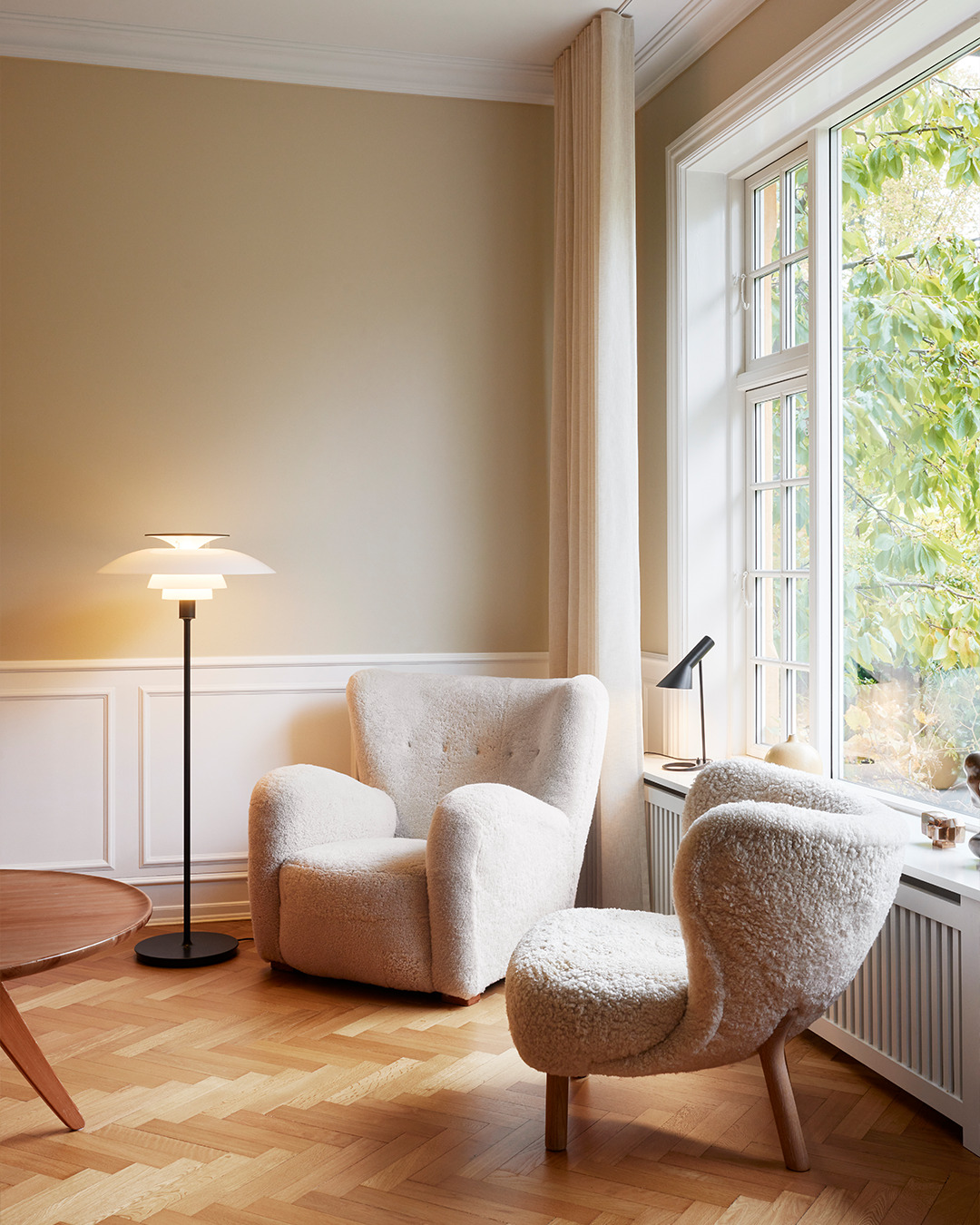 PH 80 floor lamp in white with layered shades, placed in a cozy corner by a window, © 2025 Louis Poulsen.