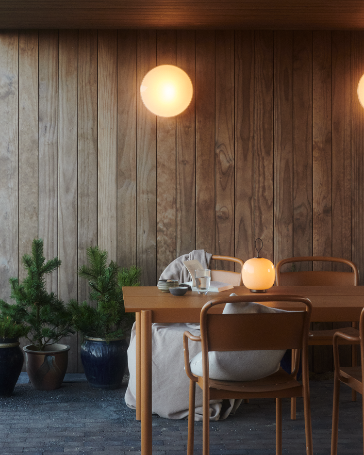 Eklipta Wall lamp glowing warmly above potted plants, © 2025 Louis Poulsen.