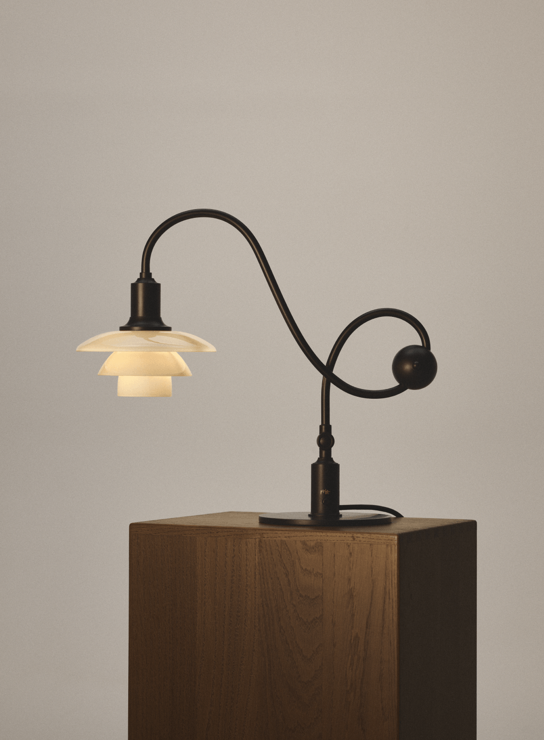 PH 1/1 Piano Lamp illuminated on a wooden plinth, © 2025 Louis Poulsen.