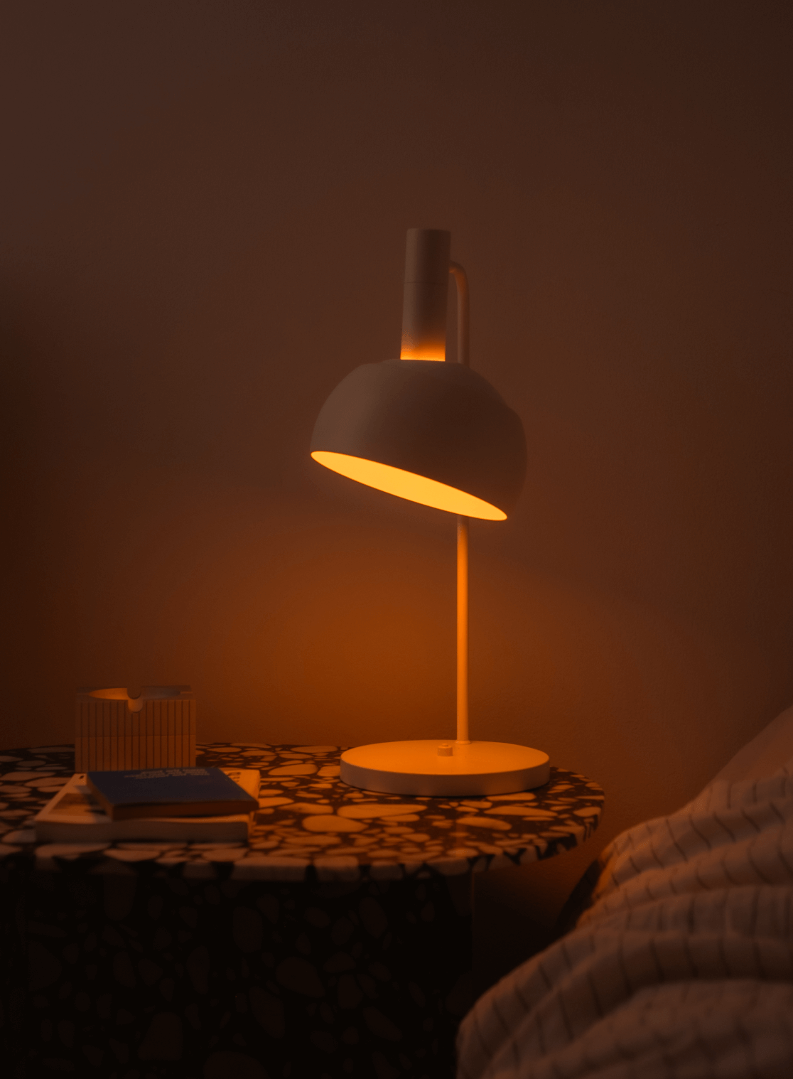 FJ Element Table Lamp in White glowing warmly on patterned bedside table, © 2025 Louis Poulsen.