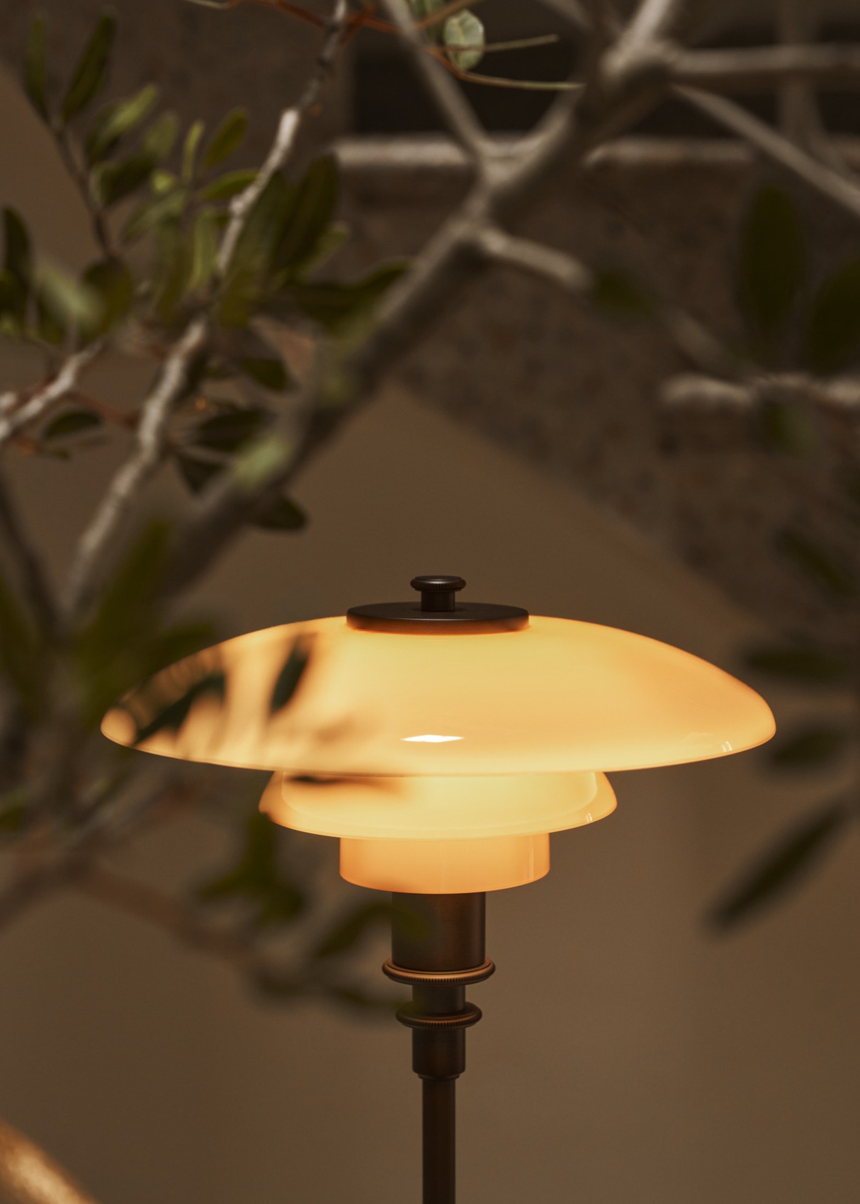 PH 2/1 Table Lamp Limited Edition 2024 spendet warmes Licht neben Innenbepflanzung, © 2025 Louis Poulsen.