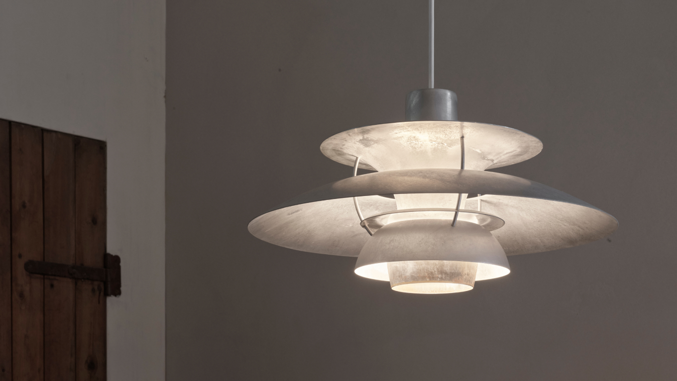 PH 5 Retake Pendelleuchte spendet weiches Licht in schlichtem Raum mit Holztür, © 2025 Louis Poulsen.