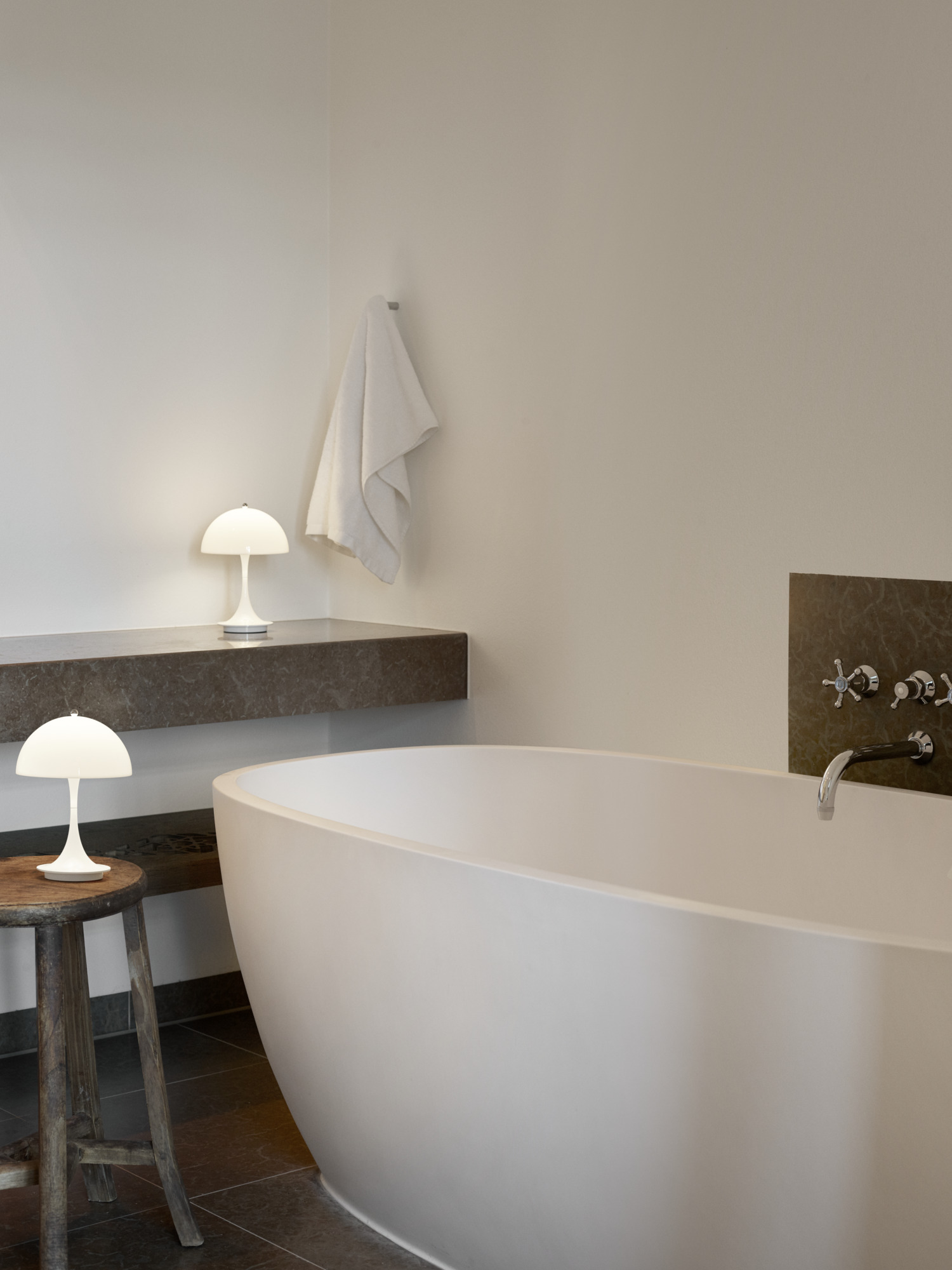 Panthella 160 Portable lamps beside freestanding bathtub in soft light, © 2025 Louis Poulsen.