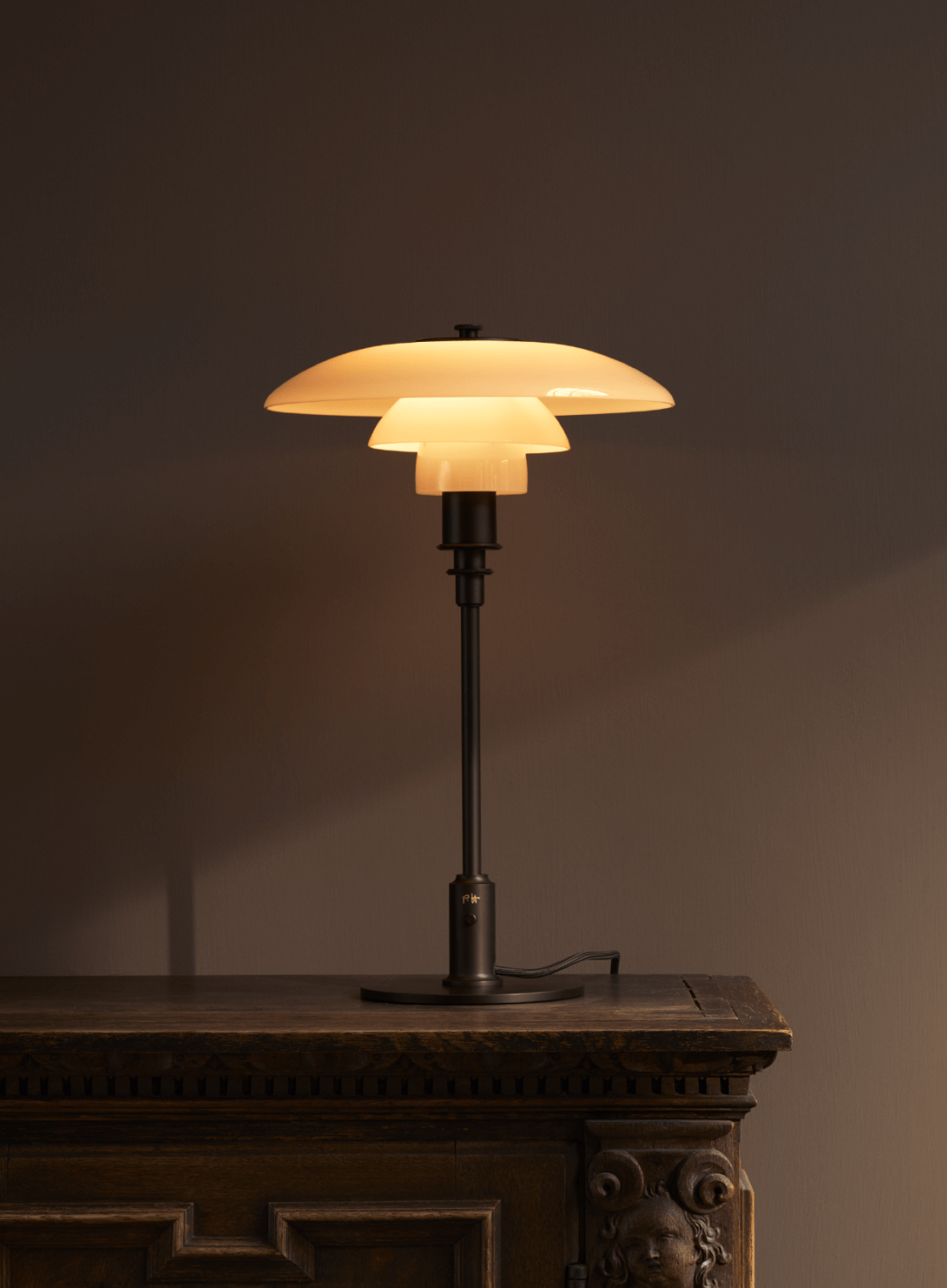 PH 3/2 Dusty Terracotta Limited Edition 2025 auf einem geschnitzten Holzschrank im warmen Licht, © 2025 Louis Poulsen.