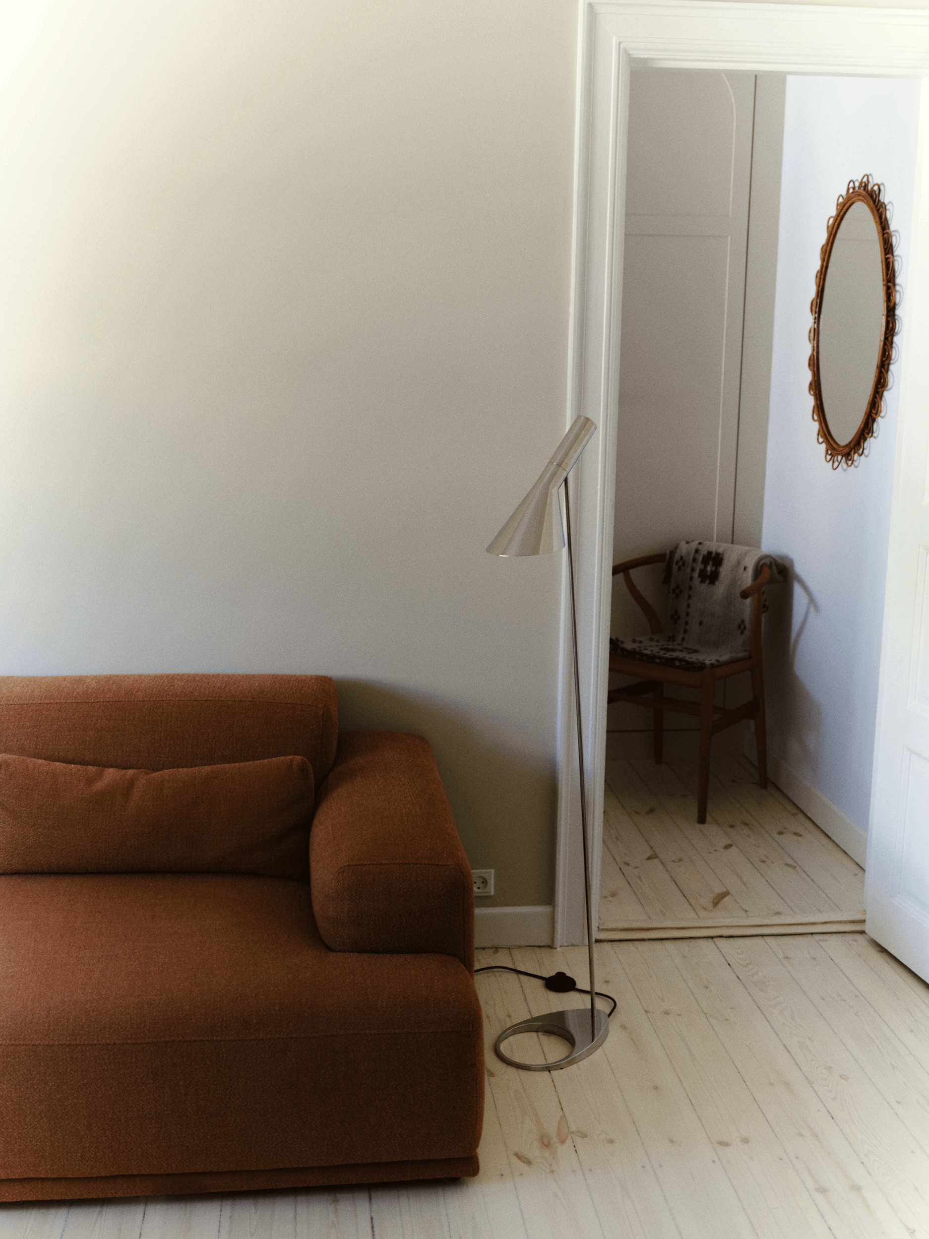AJ Floor Lamp beside sofa creating focused reading light in living room, © 2025 Louis Poulsen.