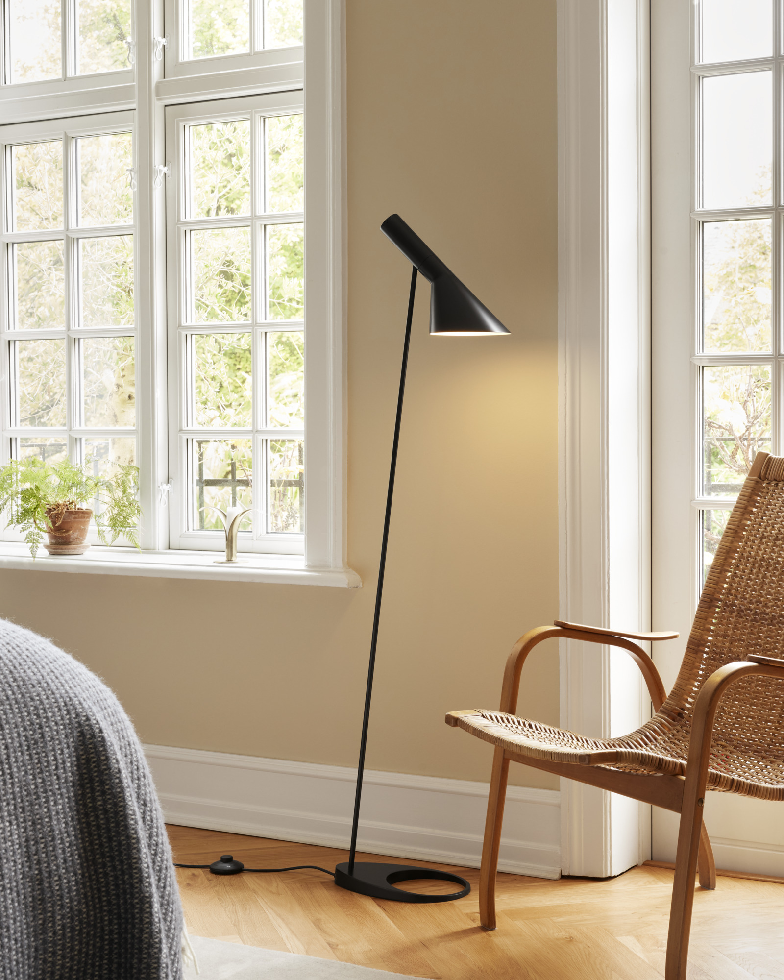 AJ Floor lamp in black placed in a living room, © 2025 Louis Poulsen.