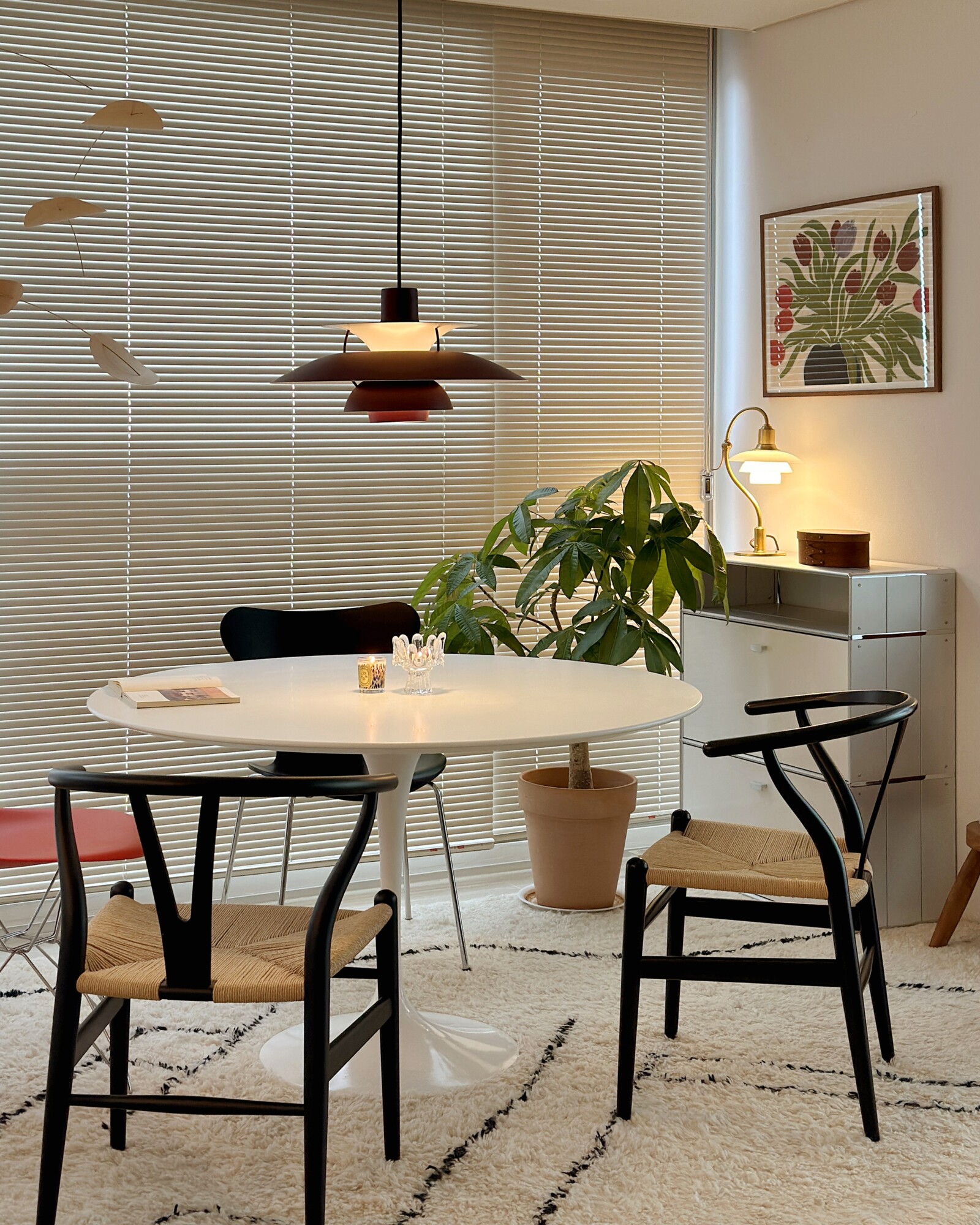 PH 5 pendant in burgundy hanging above a dining table in a living room, © 2025 Louis Poulsen.